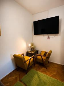 a living room with two chairs and a flat screen tv at Studio apartman Hinko in Đakovo