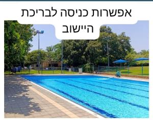 a large swimming pool with a sign that reads njp nojad istg at בצל הדקל in Bet Leẖem HaGelilit