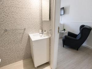 a bathroom with a sink and a black chair at Casa da Aida - Fuzeta in Fuzeta