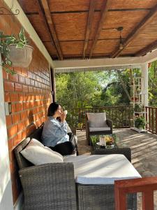 a woman sitting on a porch talking on a cell phone at Cabaña Moyobamba in Moyobamba