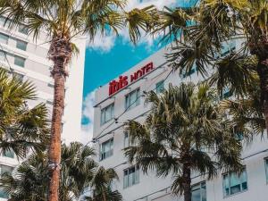 a tall white building with a red sign on it at ibis Sydney Olympic Park in Sydney