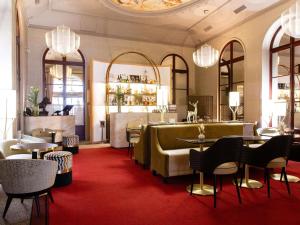 a restaurant with tables and chairs on a red carpet at Carlton Hotel Lyon - MGallery Collection in Lyon