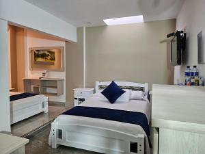 a bedroom with two beds and a tv on the wall at Hotel San Jeronimo Armenia in Armenia