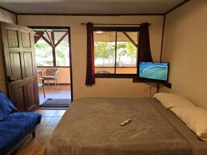 a bedroom with a bed and a tv on the wall at Outback Hermosa in Playa Hermosa