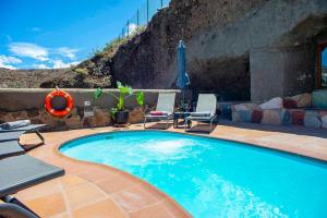 a swimming pool with two lounge chairs and a patio at Casa Cueva El Caidero By Artenatur in Artenara