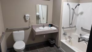 a bathroom with a toilet and a sink and a tub at Northwoods Inn and Suites in Ely +10 photos
