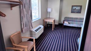 a room with a crib and a chair and a window at Northwoods Inn and Suites in Ely