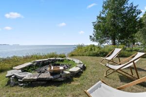 two chairs sitting around a fire pit by the water at Limestone Edge by Simple Life Rentals in Baileys Harbor