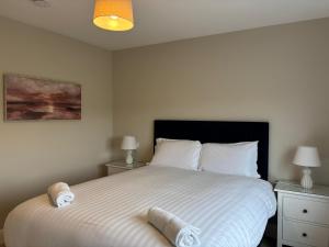 a bedroom with a large white bed with towels on it at Creevy Cove cottage in Kildoney