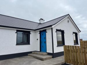 a white house with a blue door at Creevy Cove cottage in Kildoney