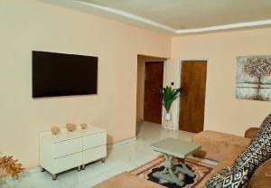a living room with a flat screen tv on the wall at Mirai Apartments in Harare