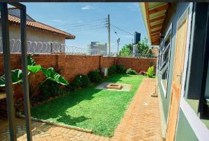 a backyard with a brick wall and a yard withgrass at Mirai Apartments in Harare