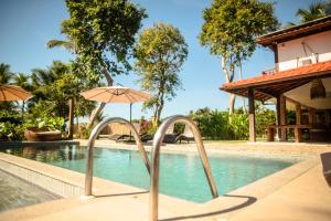 a swimming pool with an umbrella next to a resort at Pousada Villa Tainá - Arraial d'Ajuda, Bahia in Arraial d'Ajuda +40 photos
