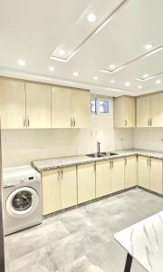 a kitchen with white cabinets and a washer and dryer at Andre Luxury Apart in Laayoune