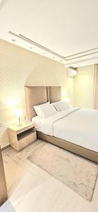 a bedroom with a large white bed and a table at Andre Luxury Apart in Laayoune