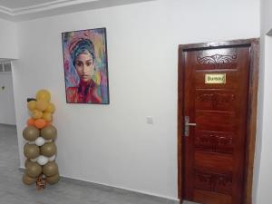 a painting of a woman next to a door with balloons at HOTEL DU PRINCE Bingerville in Bingerville