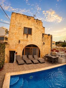 a brick building with a swimming pool in front of it at Ta Speranza Farmhouse in Victoria