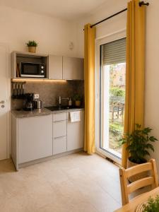 a kitchen with a sink and a microwave and a window at OMNI - Homes - Waldstraße in Falkensee