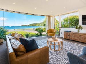 ein Wohnzimmer mit Ledersofa und einem großen Fenster in der Unterkunft Blackpool Bayside - Stay Waiheke in Oneroa