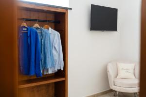 a closet with blue shirts and a chair and a television at GrandPa's House in Sorrento