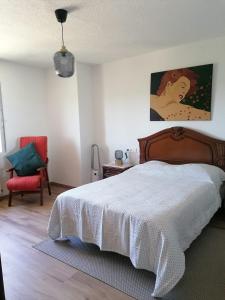 a bedroom with a large bed and a red chair at La Casa del Cribero in Mieza