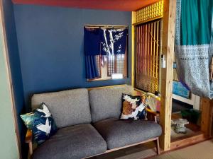 a couch in a room with a blue wall at Mitte Lodge 健やかな大人達の田舎ホームステイ1日1組限定で駅送迎と3食家庭料理体験付き in Atami