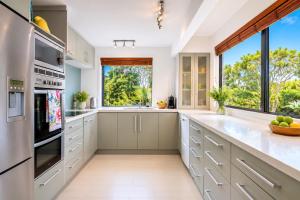 eine Küche mit weißen Schränken und einem großen Fenster in der Unterkunft Blackpool Bayside - Stay Waiheke in Oneroa + 18 Fotos
