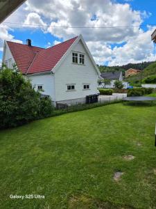 a white house with a red roof and a yard at Kristiansand Mosby1 in Kristiansand
