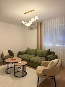 a living room with a green couch and a table at A&L Luxury Apartment in Tuzla