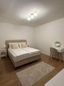 a white bedroom with a bed and a table at A&L Luxury Apartment in Tuzla