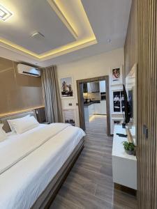 a bedroom with a large white bed and a television at Maydec Plus Homes & Apartments in Abuja