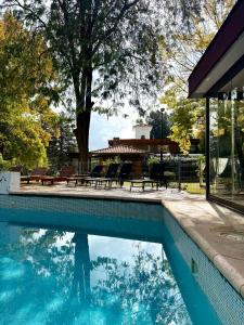 a swimming pool with tables and benches in a yard at Terra Campo Posada in Chacras de Coria