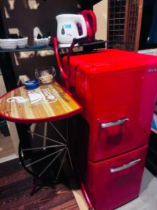 a red refrigerator with a small table next to it at Mitte Lodge 健やかな大人達の田舎ホームステイ1日1組限定で駅送迎と3食家庭料理体験付き in Atami