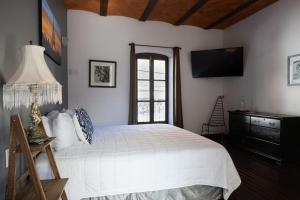 ein Schlafzimmer mit einem weißen Bett und einem Fernseher in der Unterkunft Hotel Villa 1927 in Chapala