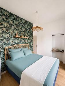 a bedroom with a blue bed with a floral wall at Le cocon de Saumur in Saumur