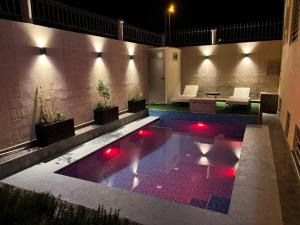 a pool with red lights in a courtyard at night at Villa Sara, Piscine et Jardin privée in Marrakesh