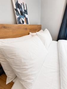 a bed with white pillows and a wooden headboard at Delwin Place - Quiet Stay & Sparkling Bathroom in Dunstable