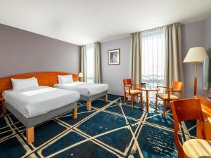 a hotel room with two beds and a table and chairs at Hotel Mercure Poznań Centrum in Poznań +250 photos