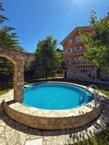 a swimming pool with a stone archway next to a building at Apartment Orange Blossom First Line & Pool 2 in Bijela
