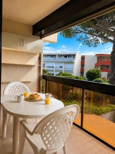 a white table and chairs on a balcony at Studio cabine - proche plage - parking - wifi in Le Grau-du-Roi