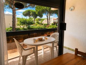 a white table and chairs on a balcony with a window at Studio cabine - proche plage - parking - wifi in Le Grau-du-Roi