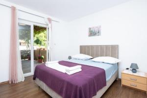 a bedroom with a bed with a purple blanket at Apartment Bogomir in Podgora