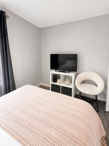 a bedroom with a bed and a tv and a chair at Delwin Place - Quiet Stay & Sparkling Bathroom in Dunstable