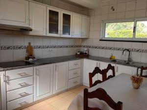 a kitchen with white cabinets and a table with chairs at Dona Emília in Horta