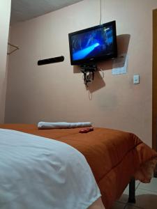 a flat screen tv hanging on a wall next to a bed at San Sebastian Hostal in Sangolquí