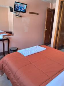 a bedroom with a bed with a television on the wall at San Sebastian Hostal in Sangolquí +12 photos