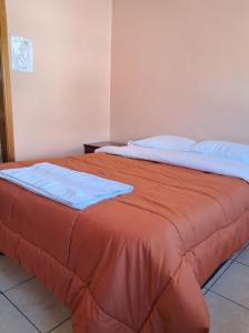 a bedroom with two beds with orange sheets and blue pillows at San Sebastian Hostal in Sangolquí