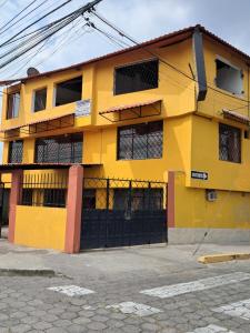 a yellow building with a black gate at San Sebastian Hostal in Sangolquí