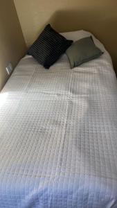 a bed with a white comforter and a pillow at Departamento Los Ceibos 2 in San Fernando del Valle de Catamarca