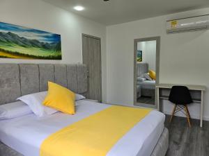 a bedroom with a bed with a yellow pillow at Hotel San Jeronimo Armenia in Armenia